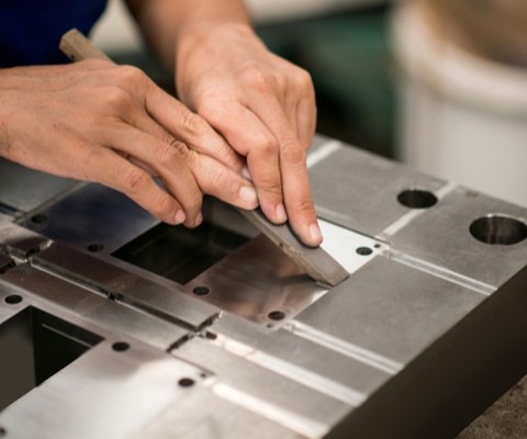 an industrial worker polishing a molding tool