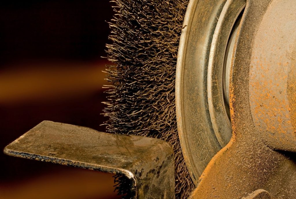 steel wire brush working on a metal part